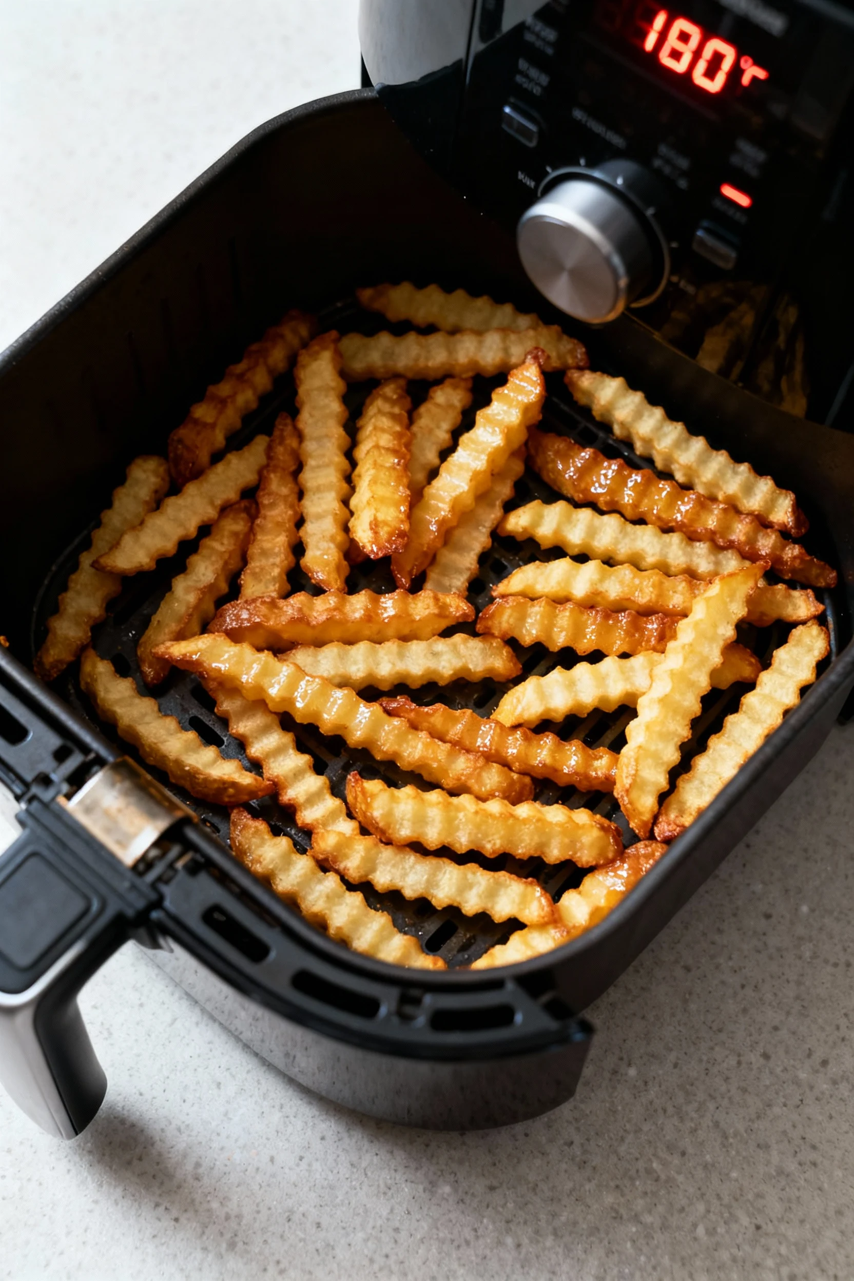 Air fryer basket in the final high-heat stage at 400°F, frozen crinkle-cut fries arranged in a single layer with deep go