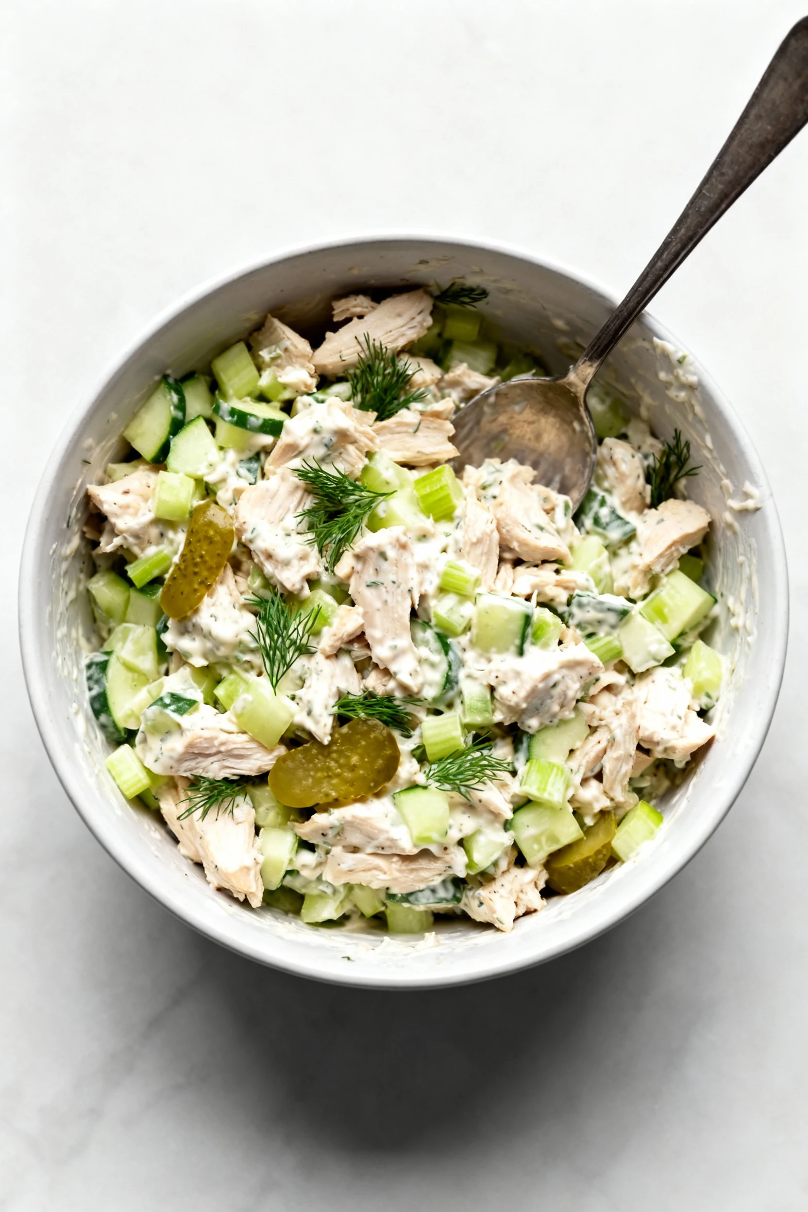 Overhead shot of freshly mixed chicken salad: juicy chopped chicken coated in ultra-creamy dressing with finely chopped 