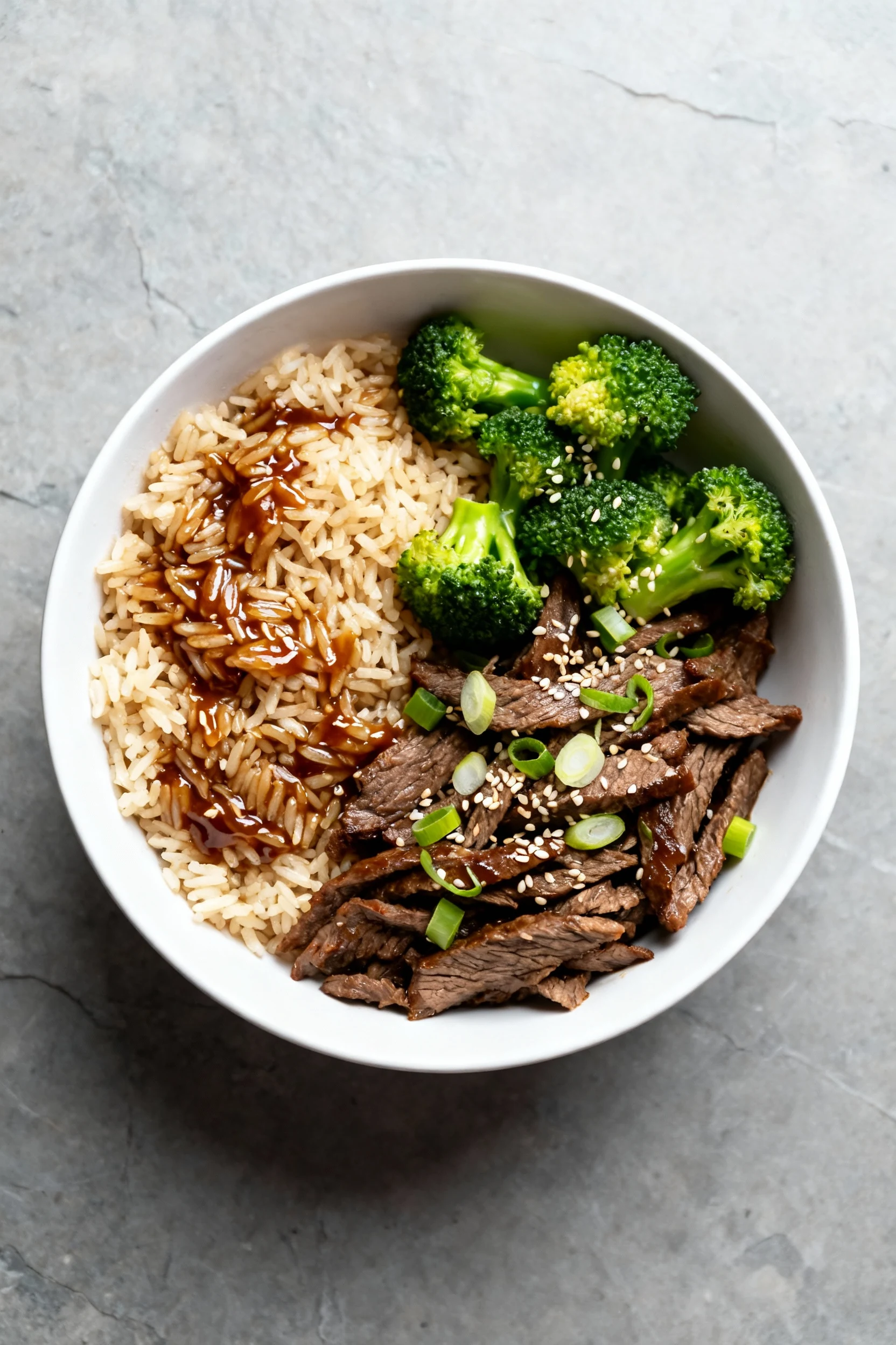 Tasty top view: Teriyaki Beef & Broccoli Rice in a wide white bowl—separate long-grain rice coated in glossy teriyaki, c