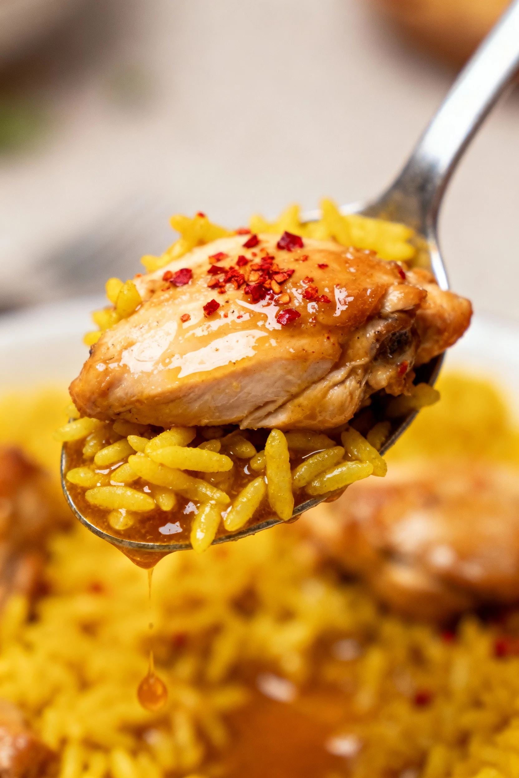 4. Macro close-up of a spoonful: juicy chicken, separate golden rice tinted by turmeric, flecks of paprika/pepper, glist
