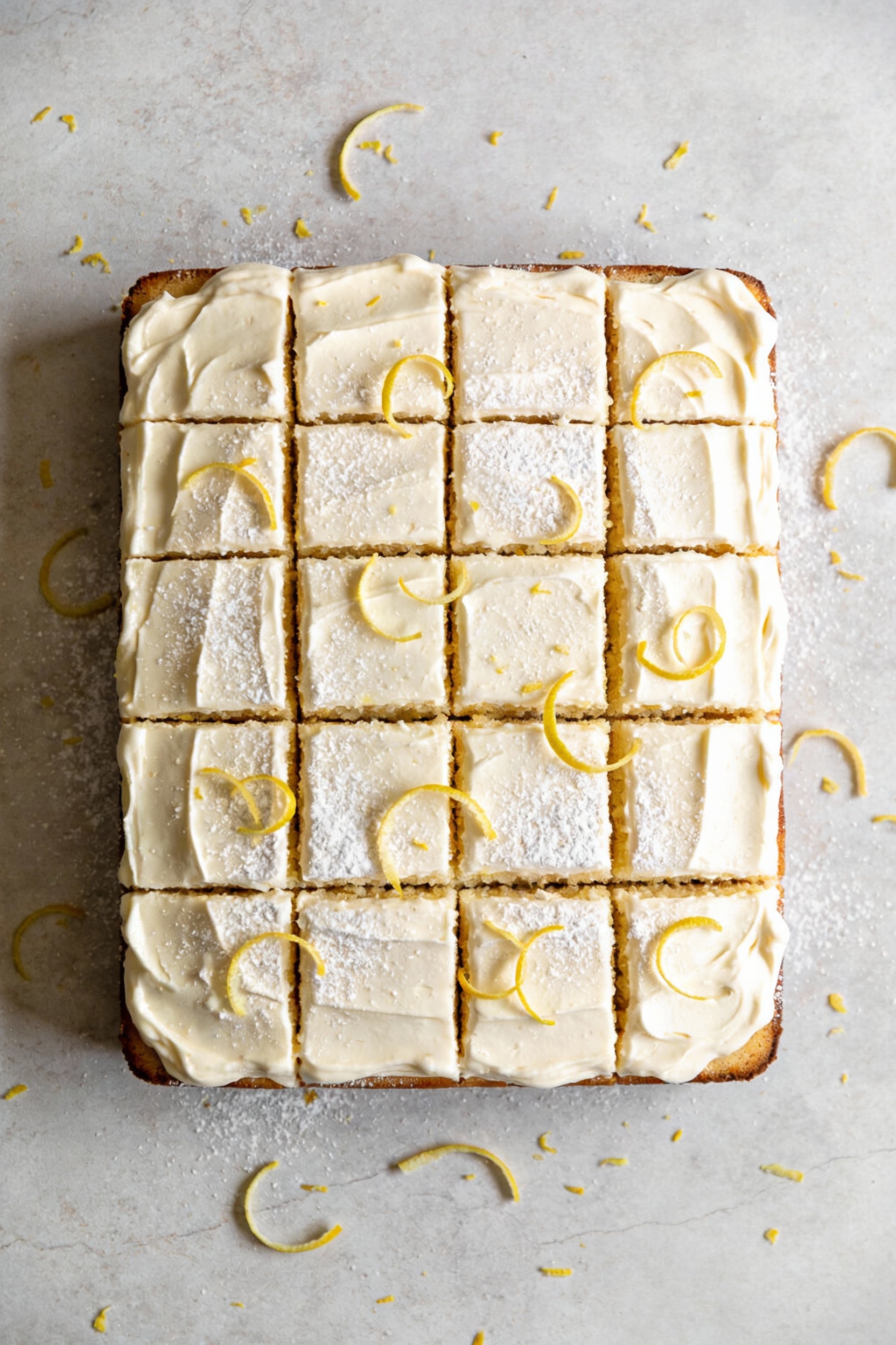 Overhead shot of a frosted 9x13 vanilla sheet cake with smooth vanilla buttercream, clean straight cut squares revealing
