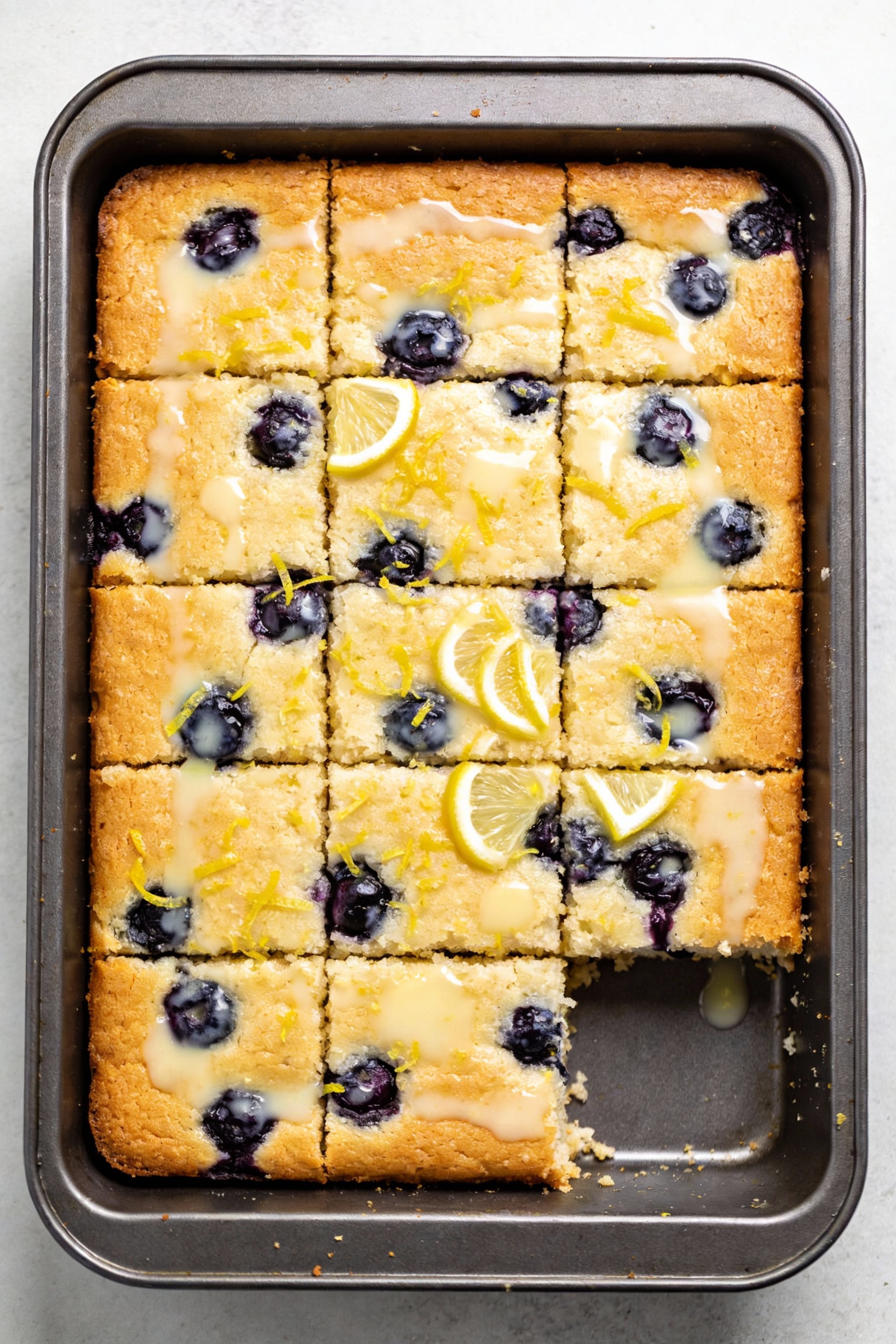 Overhead shot of Lemon Blueberry Party cake: lightly golden top with bright lemon zest and blueberry bursts peeking thro