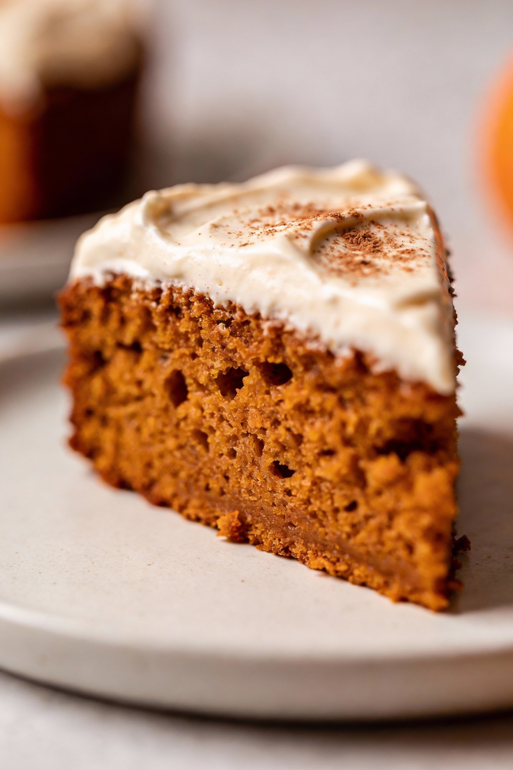 Close-up detail: Macro of a pumpkin cake slice revealing ultra-moist, plush crumb and thick cream cheese frosting with a