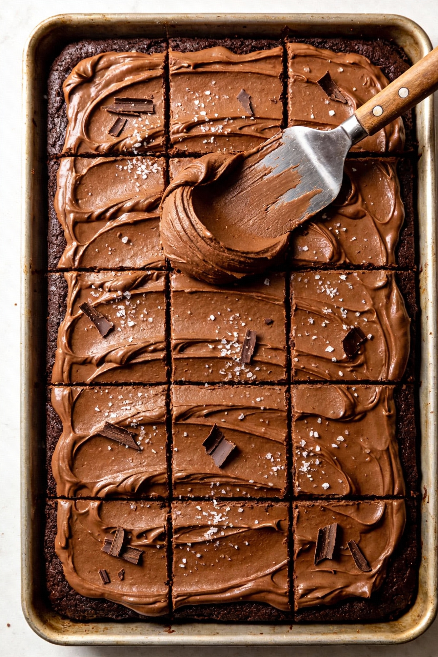Overhead shot of ultra-moist chocolate sheet cake in a 9x13 pan, smooth fudgy frosting layer with neat spatula swoops, s