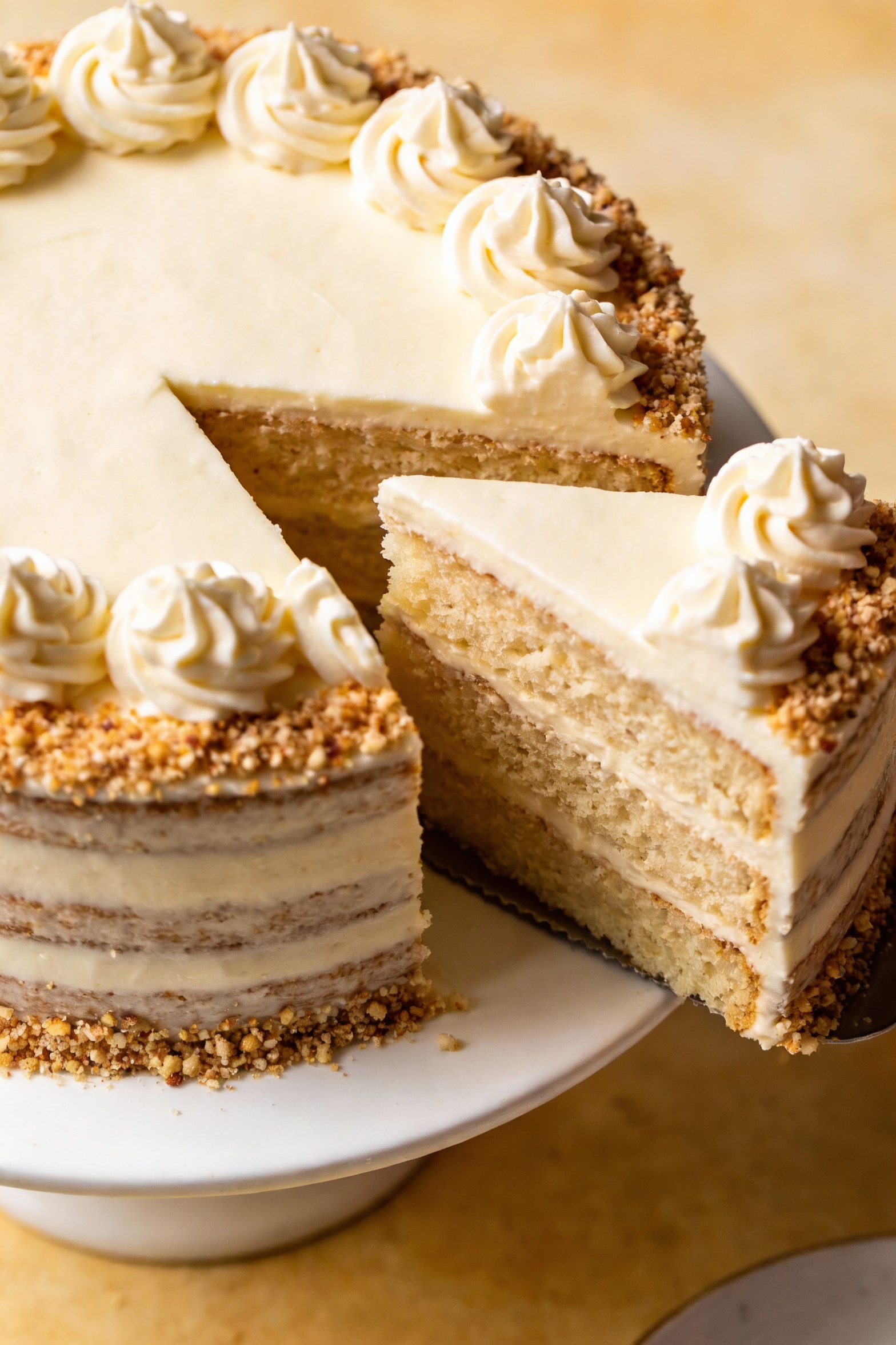Overhead shot of a vanilla celebration layer cake with smooth buttercream swirls and a dense sprinkle halo, cleanly stac