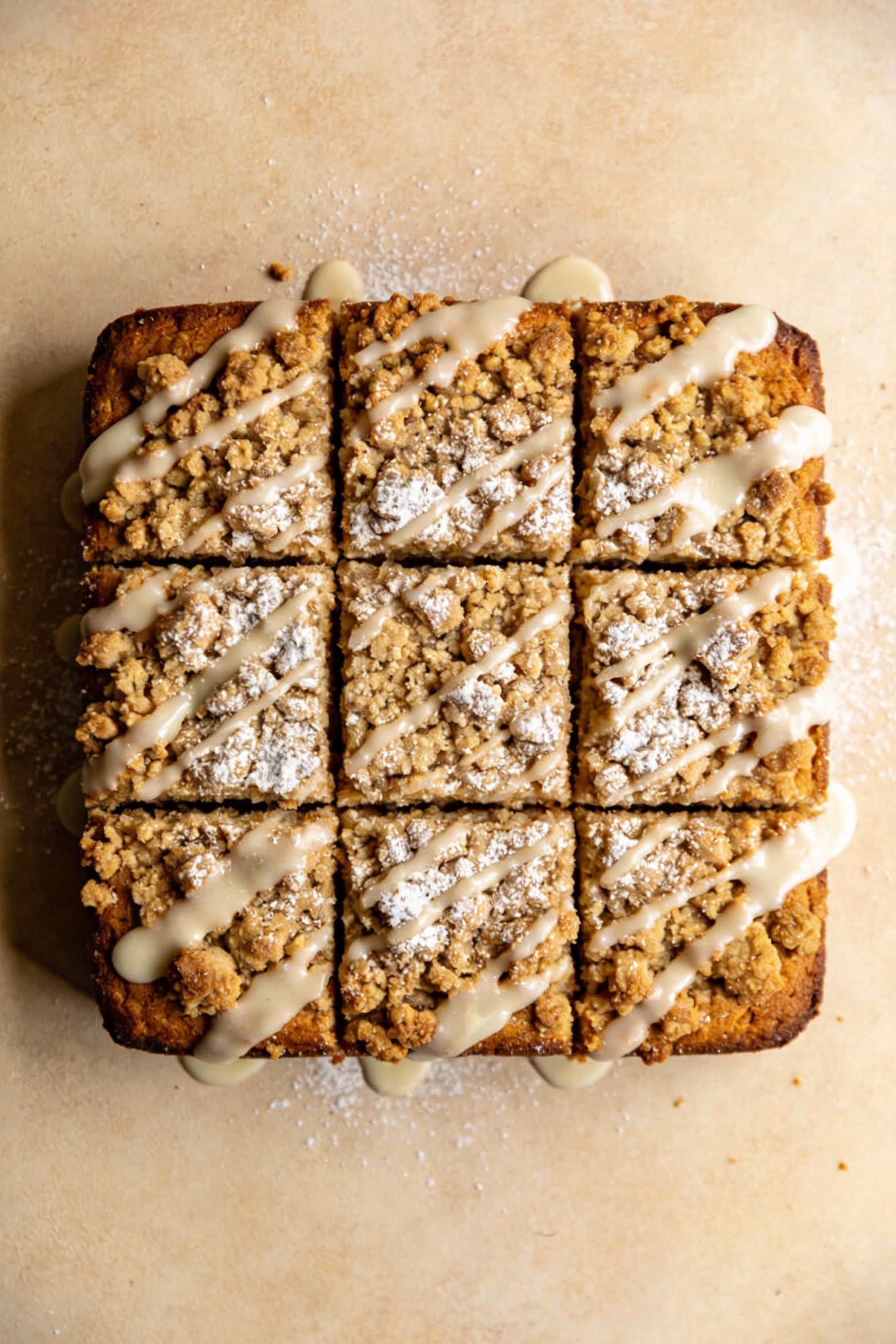 Overhead shot of the finished coffee cake sliced into neat squares, crunchy streusel layer across the top with a light p