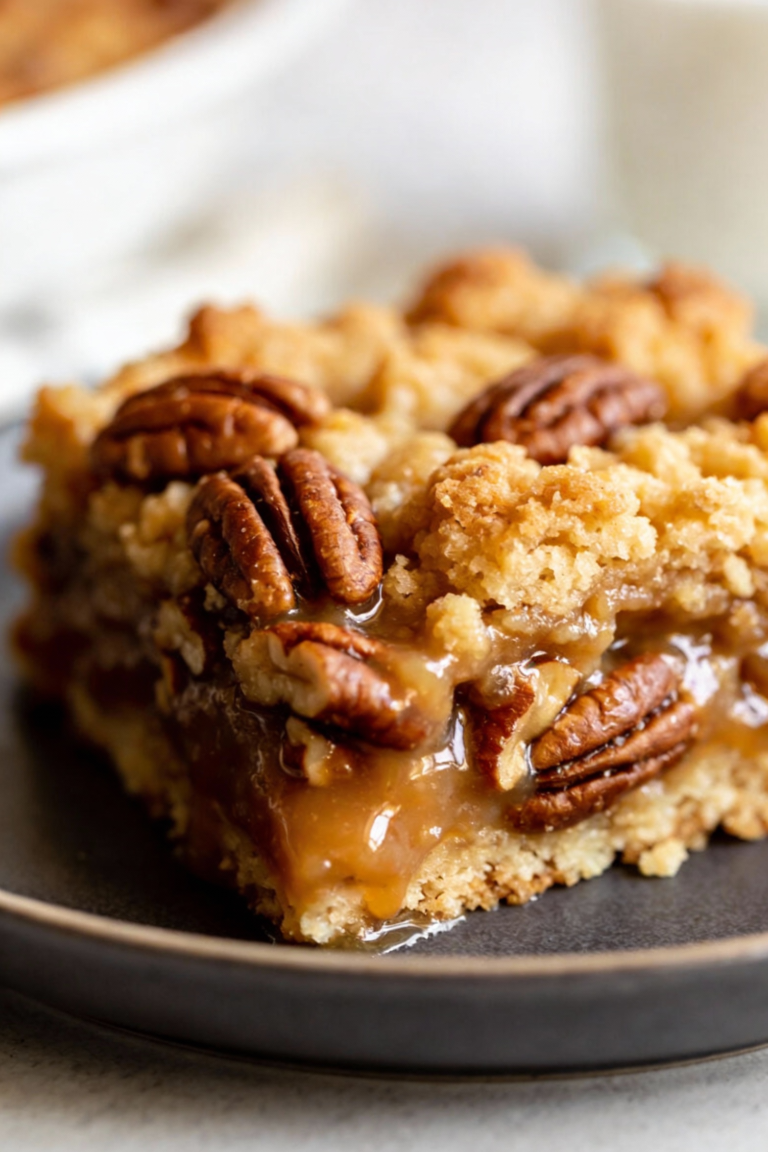 Close-up detail of a warm slice of pecan pie dump cake showing distinct layers—sticky caramel-pecan base and crunchy gol