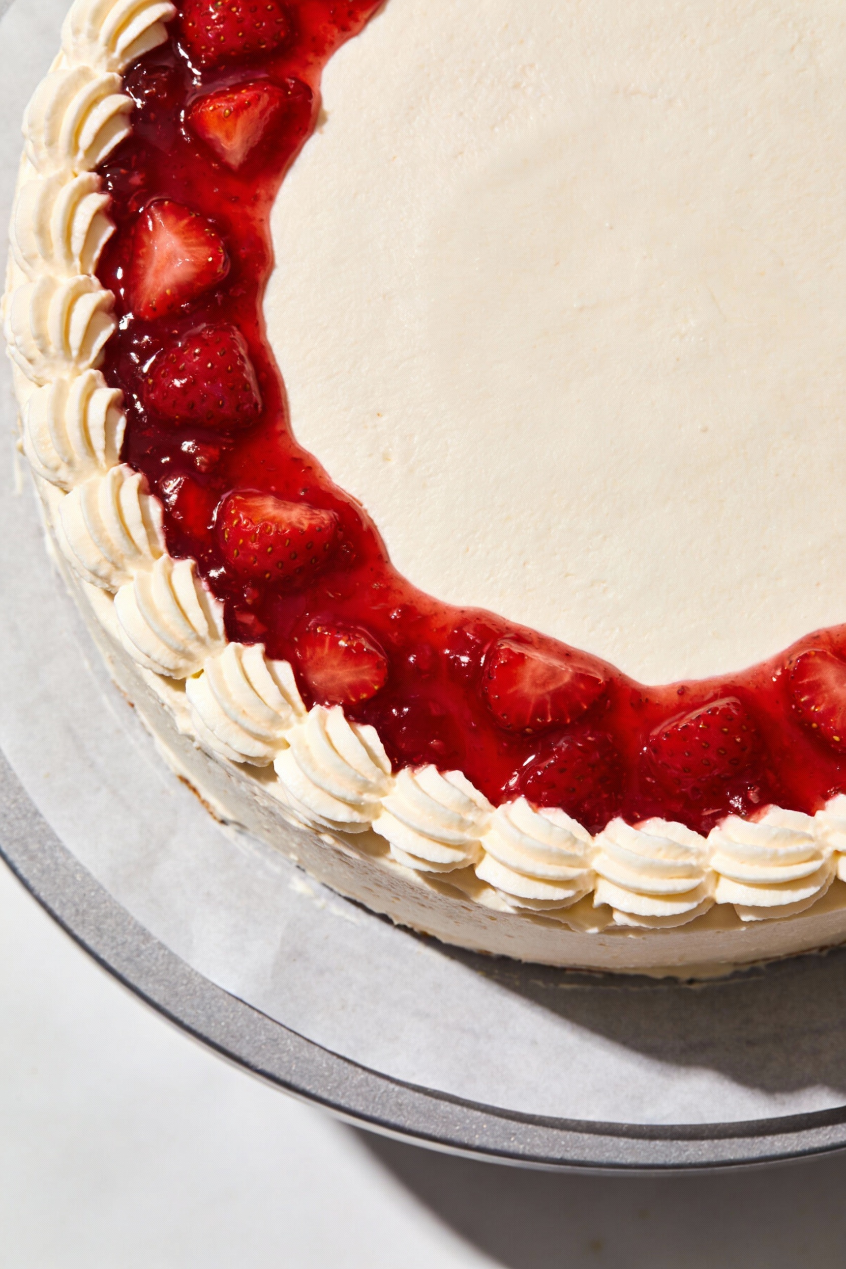 Overhead shot of cake assembly: buttercream dam piped around an 8-inch layer holding jammy strawberry compote; thickened