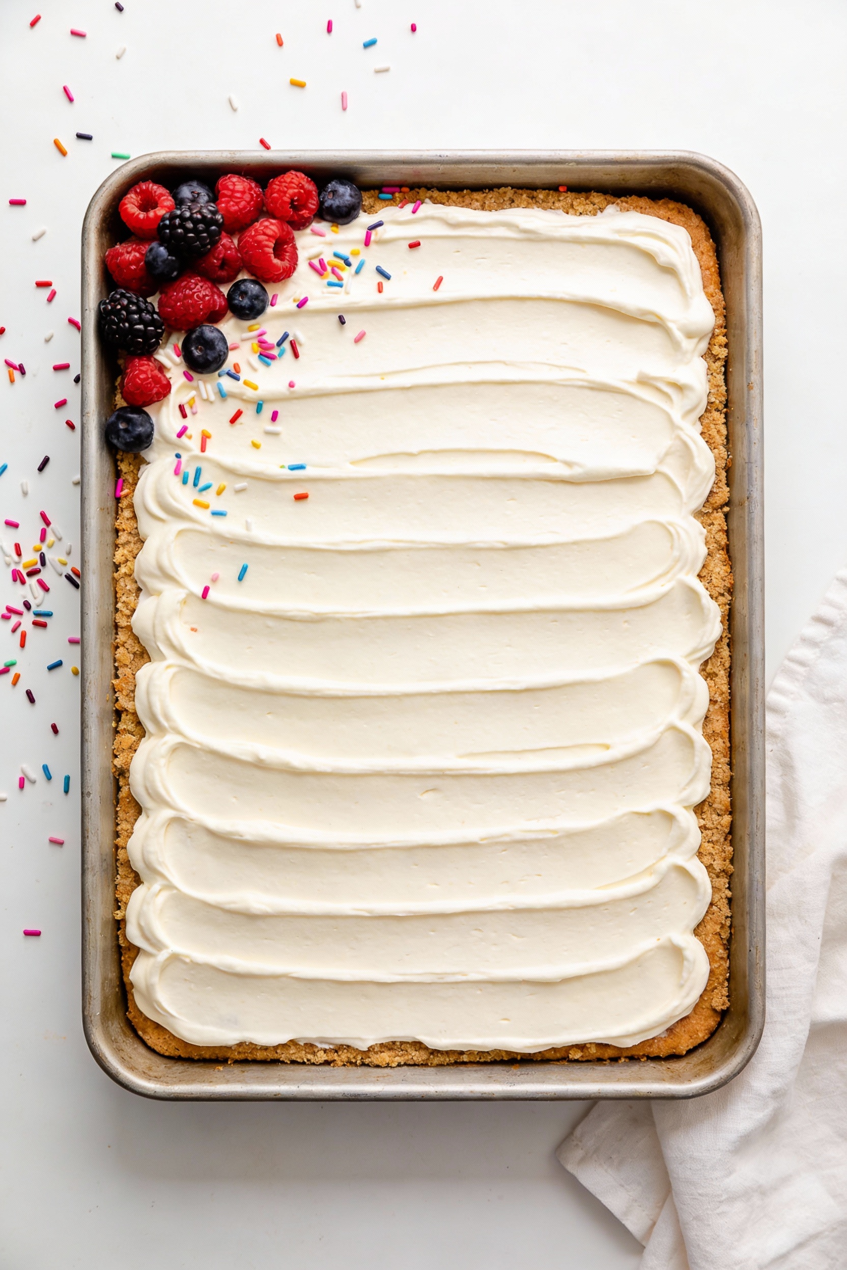 3. Overhead shot of a frosted vegan vanilla sheet cake in a 9x13 pan with a neat crumb coat and final swirled buttercrea