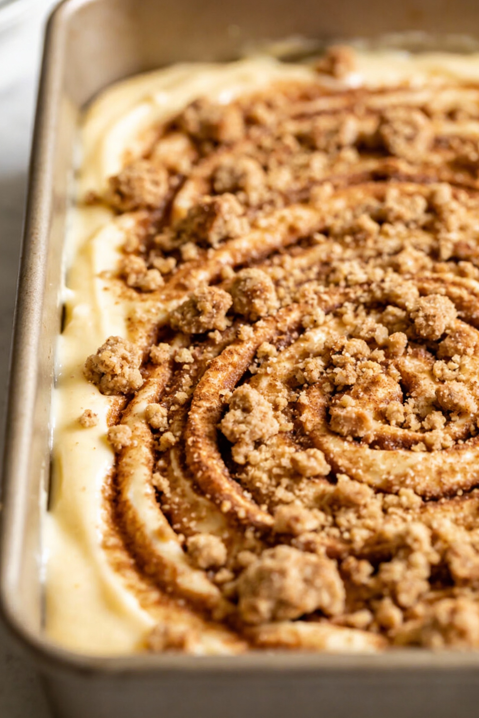 Coffee cake being prepared in the pan: thick vanilla batter partially spread with a generous layer of streusel sprinkled