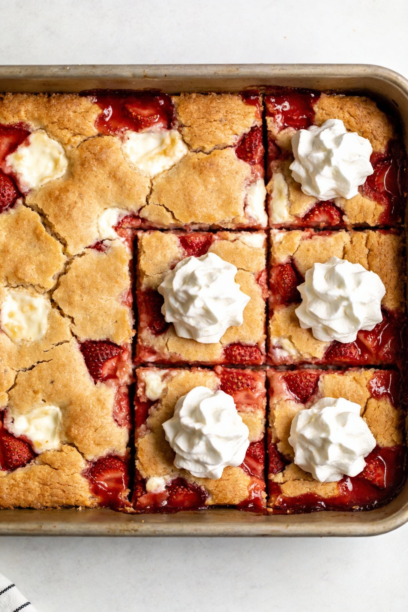 Tasty top-view of strawberry cheesecake dump cake after resting: cracked golden crust with visible cream cheese pockets 