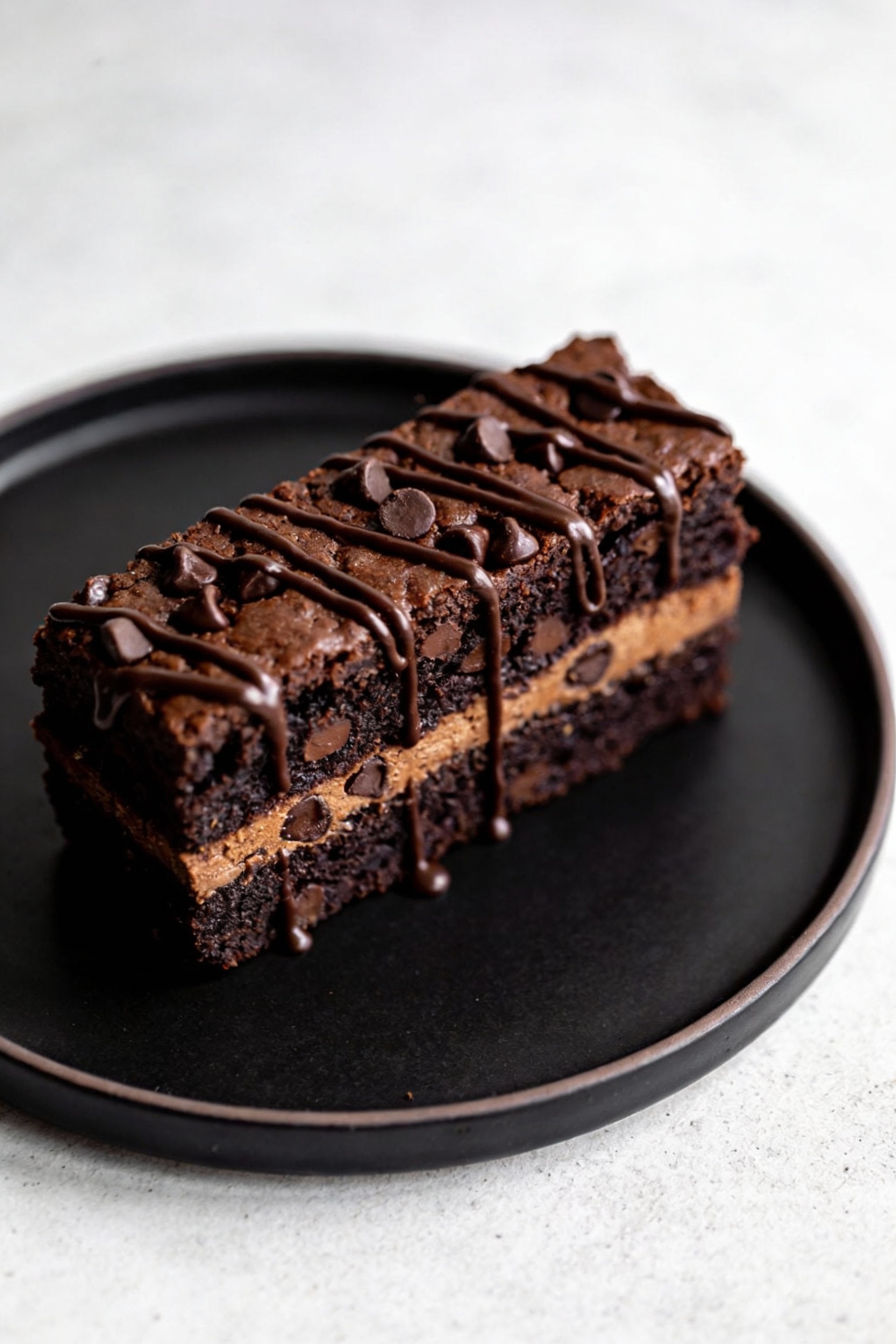 Final plated Chocolate Fudge Upgrade slice: dark, brownie-adjacent crumb studded with chocolate chips, subtle espresso f