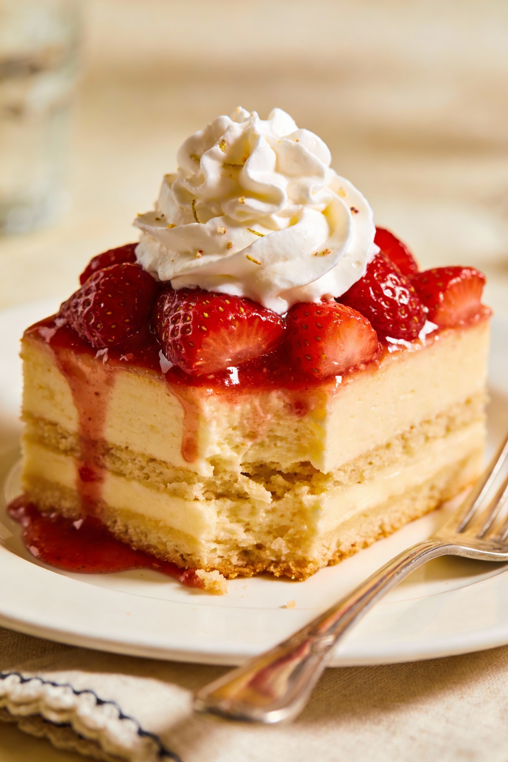 Final plated square of strawberry shortcake sheet cake: vanilla cake topped with macerated strawberries and stabilized w
