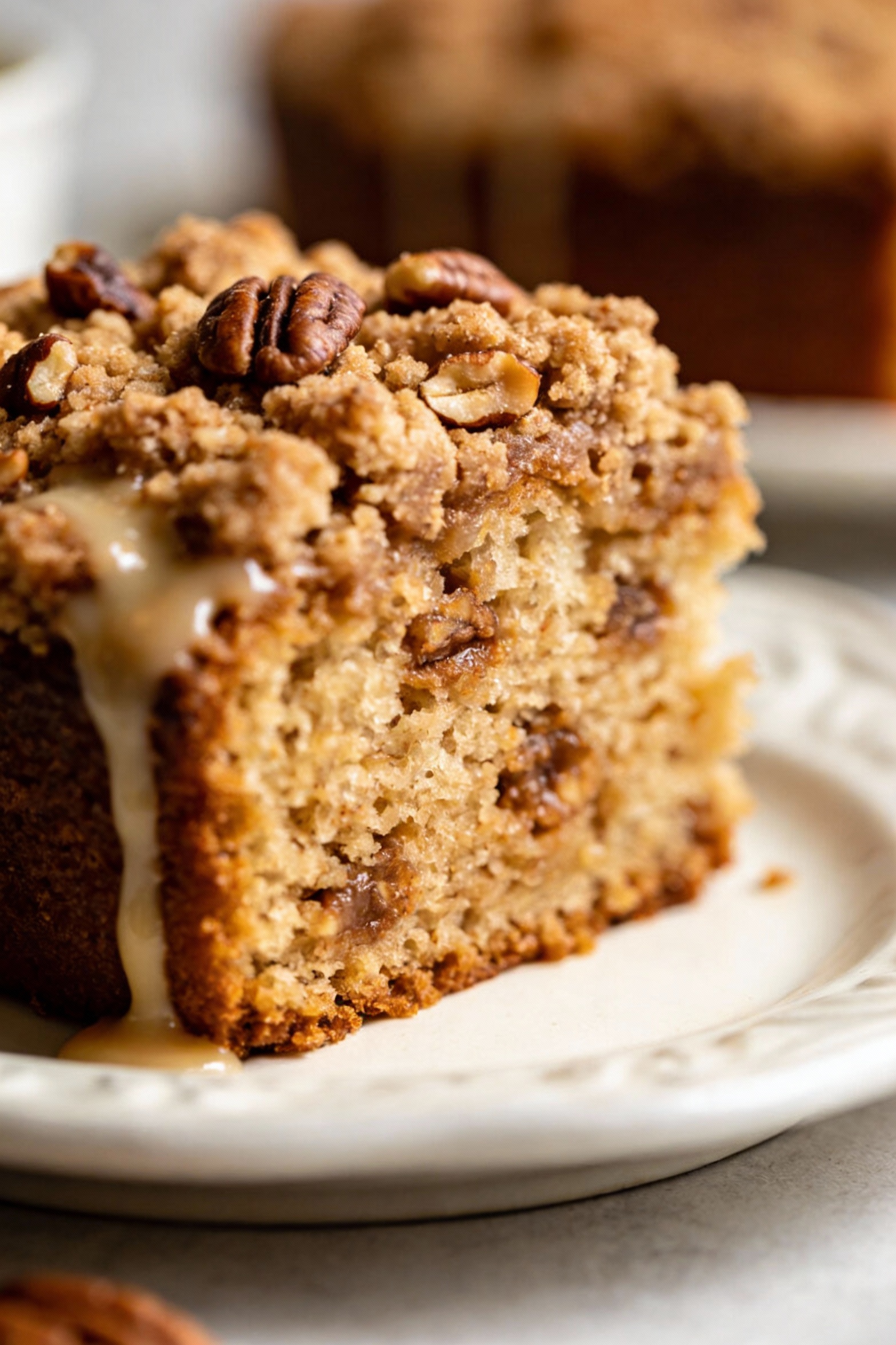 Beautifully plated slice of cinnamon-streusel coffee cake on a white ceramic dessert plate, moist tender crumb with a th